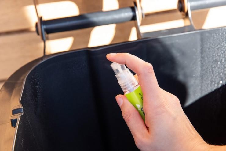 Biotonnendeo Eine Hand hält eine Sprühflache und sprüht den Rand einer Biotonne ein