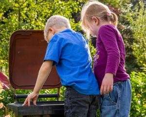 2 kleine Kinder schauen in eine geöffnete Biotonne