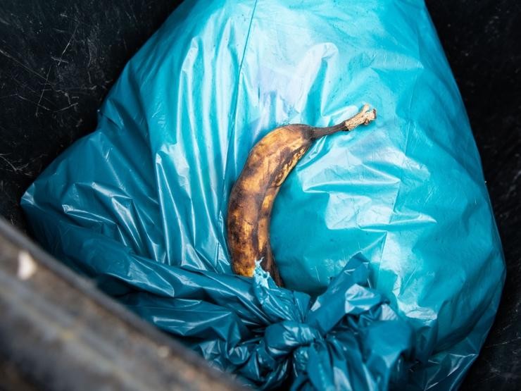 Banane liegt in der Restmülltonne auf einem blauen Sack