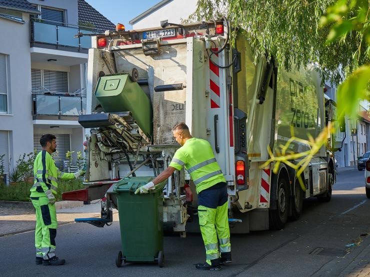 Zwei Müllwerker leeren die Abfalltonnen im Müllfahrzeug.