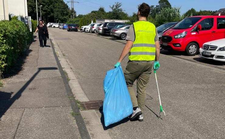 Ein Mann mit Müllsack und Greifzange auf der Straße