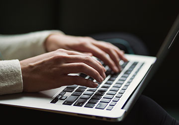 Unser Onlineservice Hände tippen etwas in einen geöffneten Laptop.
