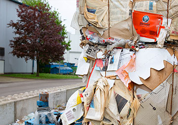 An einer Straße steht ein Container mit zusammengepressten Altpapier