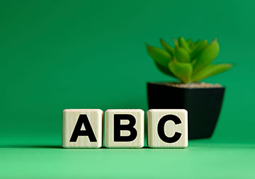 Drei Holzwürfel zeigen die Buchstaben A, B und C.